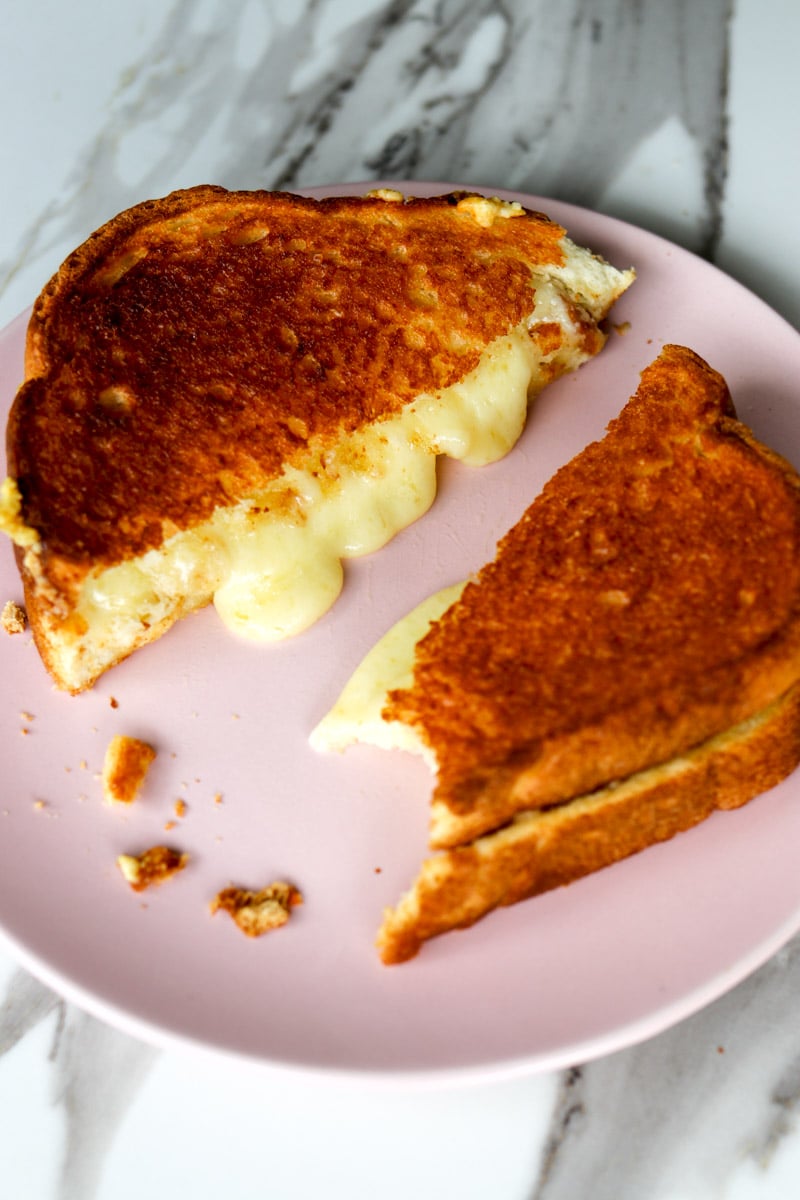 an air fryer grilled cheese on a plate with a bite taken out of it.