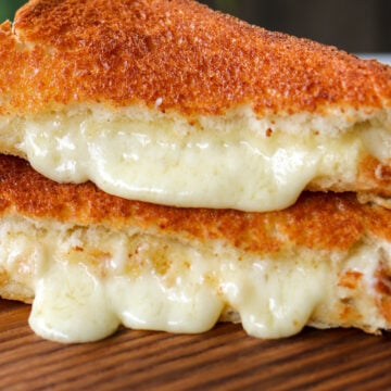 an air fryer grilled cheese cut in half with cheese oozing out of it.
