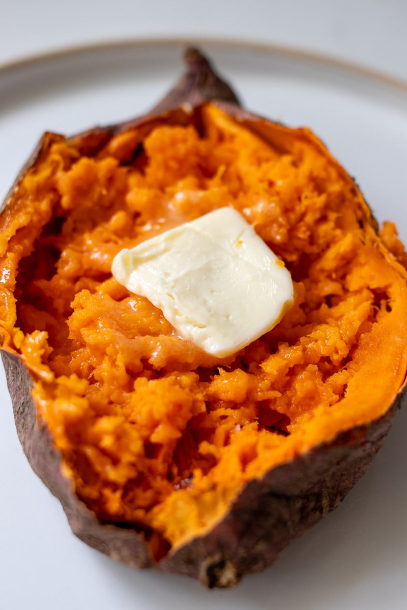 a split open microwaved sweet potato with melted butter, honey and flaky salt.