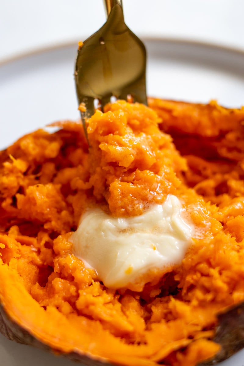 a fork showing the perfectly fluffy steamed interior of a microwaved sweet potato.