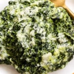 a white bowl full of steak house style creamed spinach.