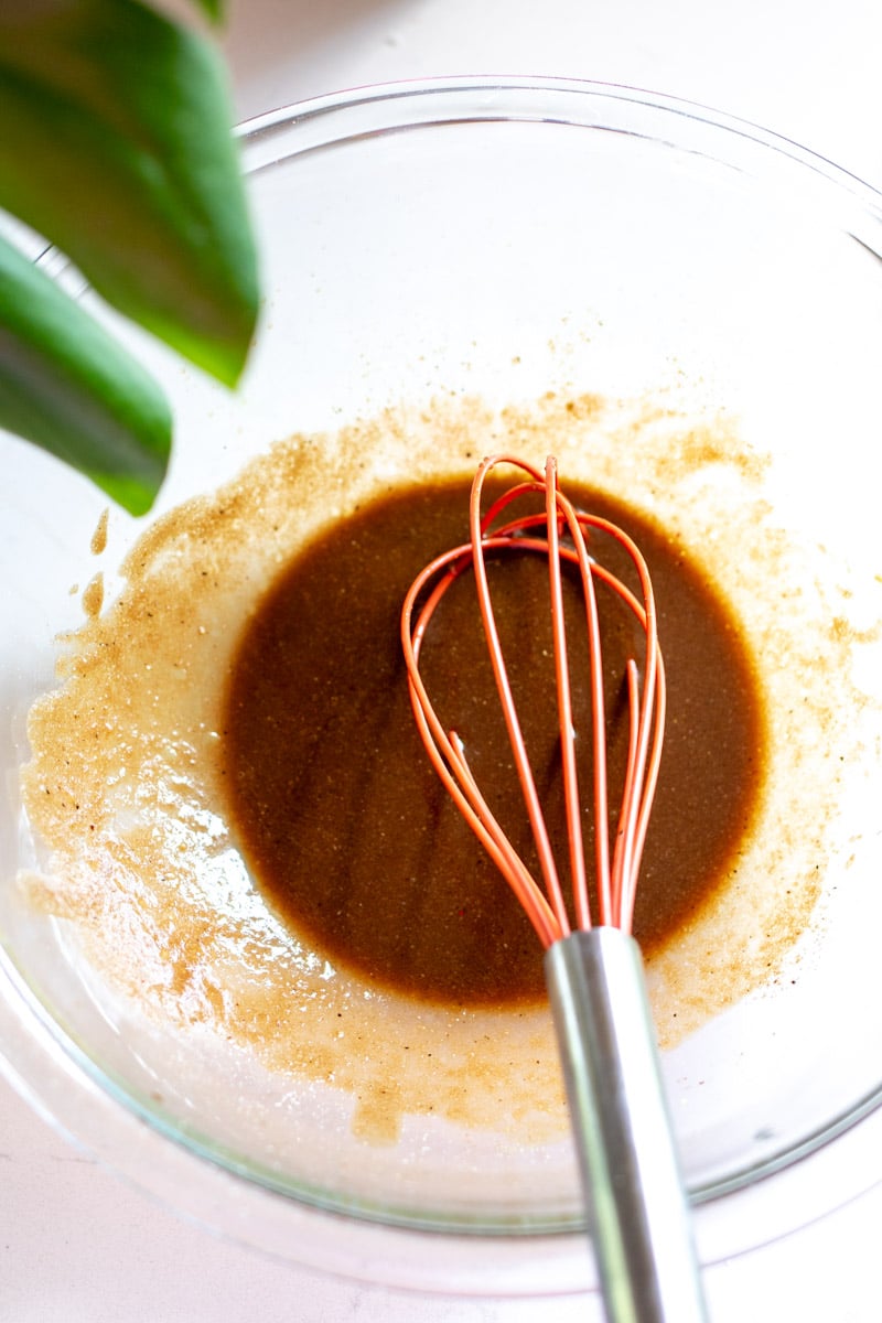 balsamic marinade in a glass bowl with an orange whisk in it. 