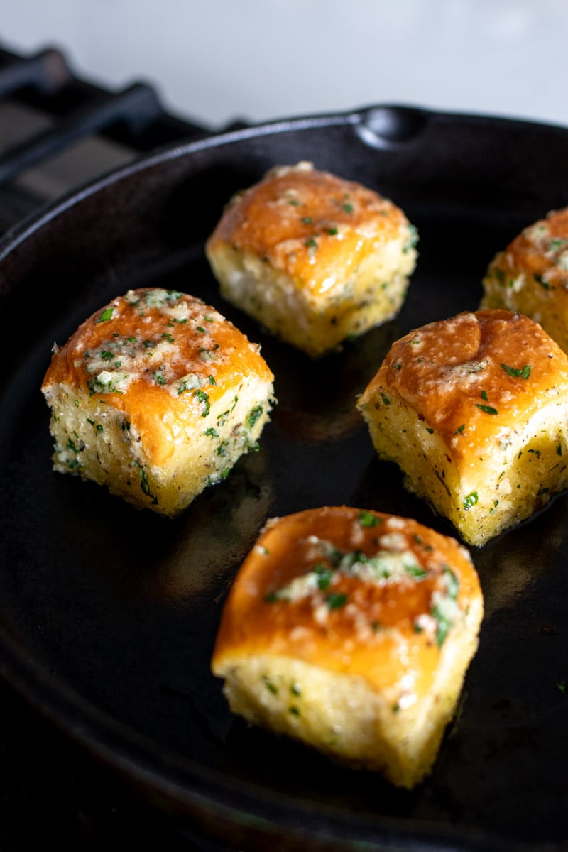 garlic bread hawaiian bites being fried up in a cast iron skillet. 