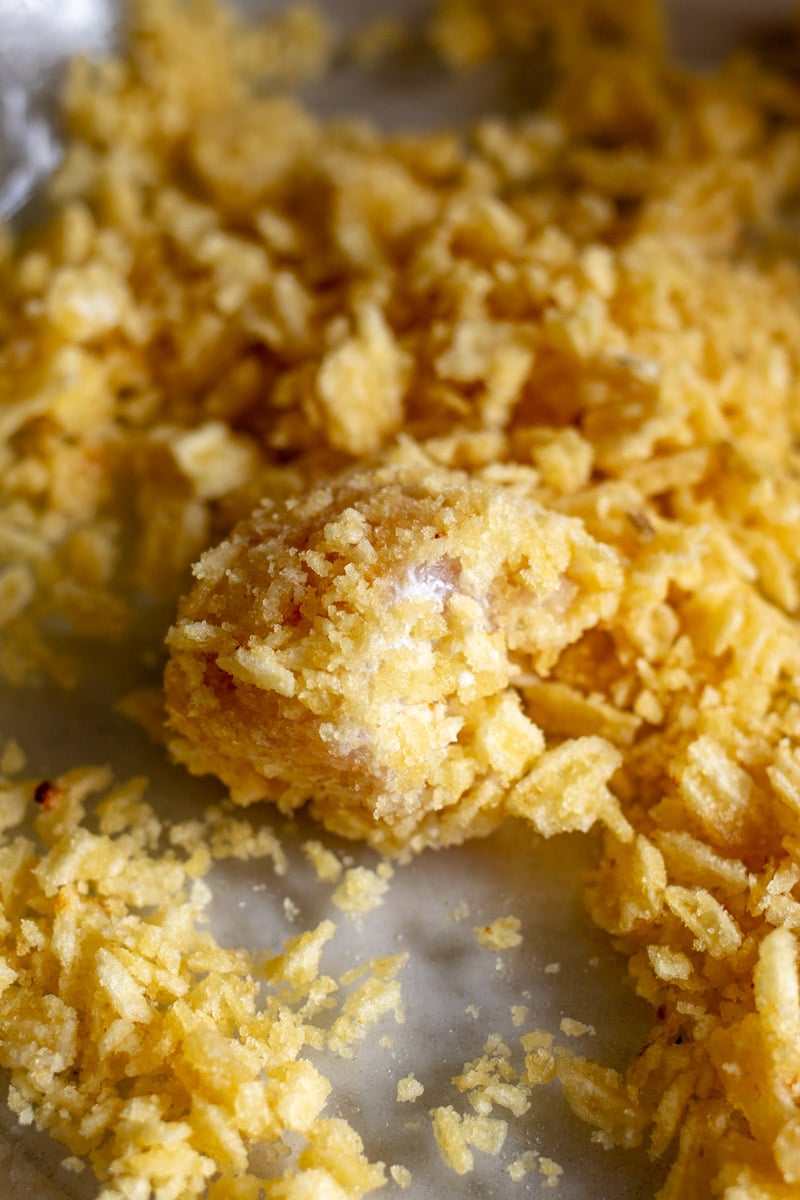 a piece of chicken rolled around in crushed potato chips. 