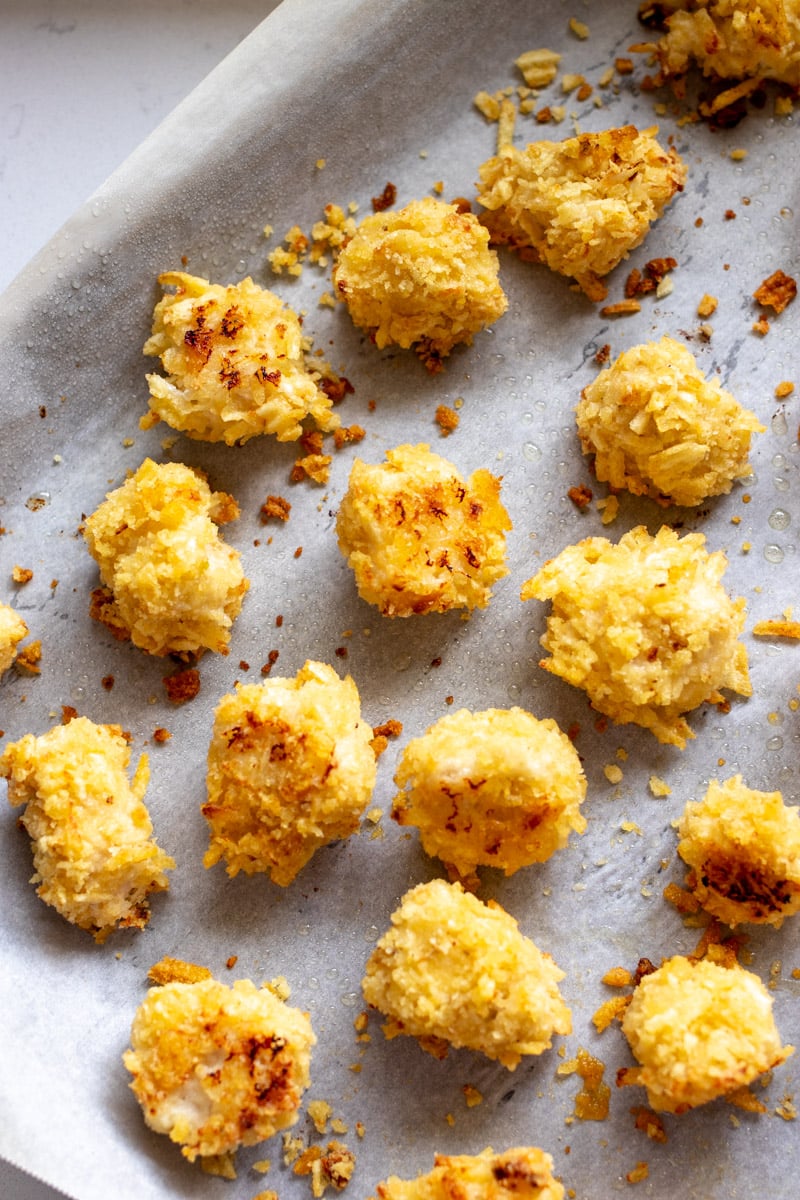 golden brown popcorn chicken nuggets on a baking sheet after coming out of the oven. 