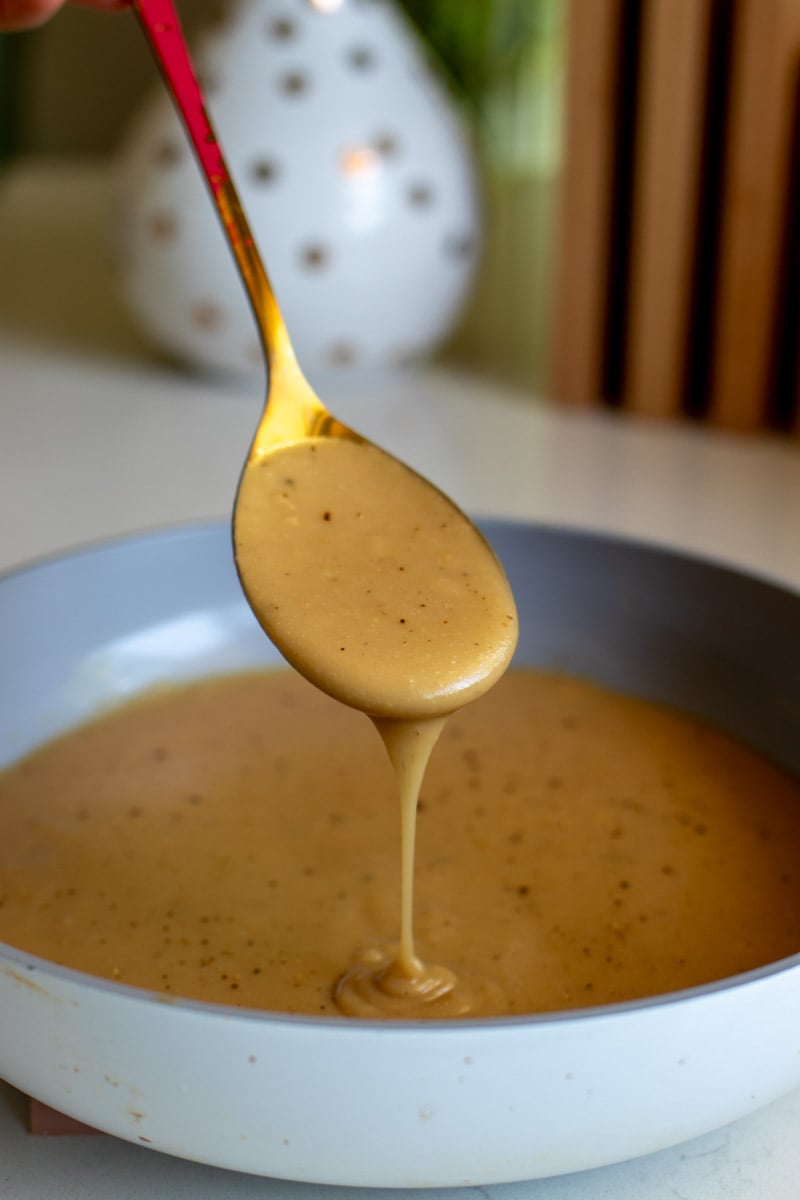 a spoon pouring gravy out onto a pan. 