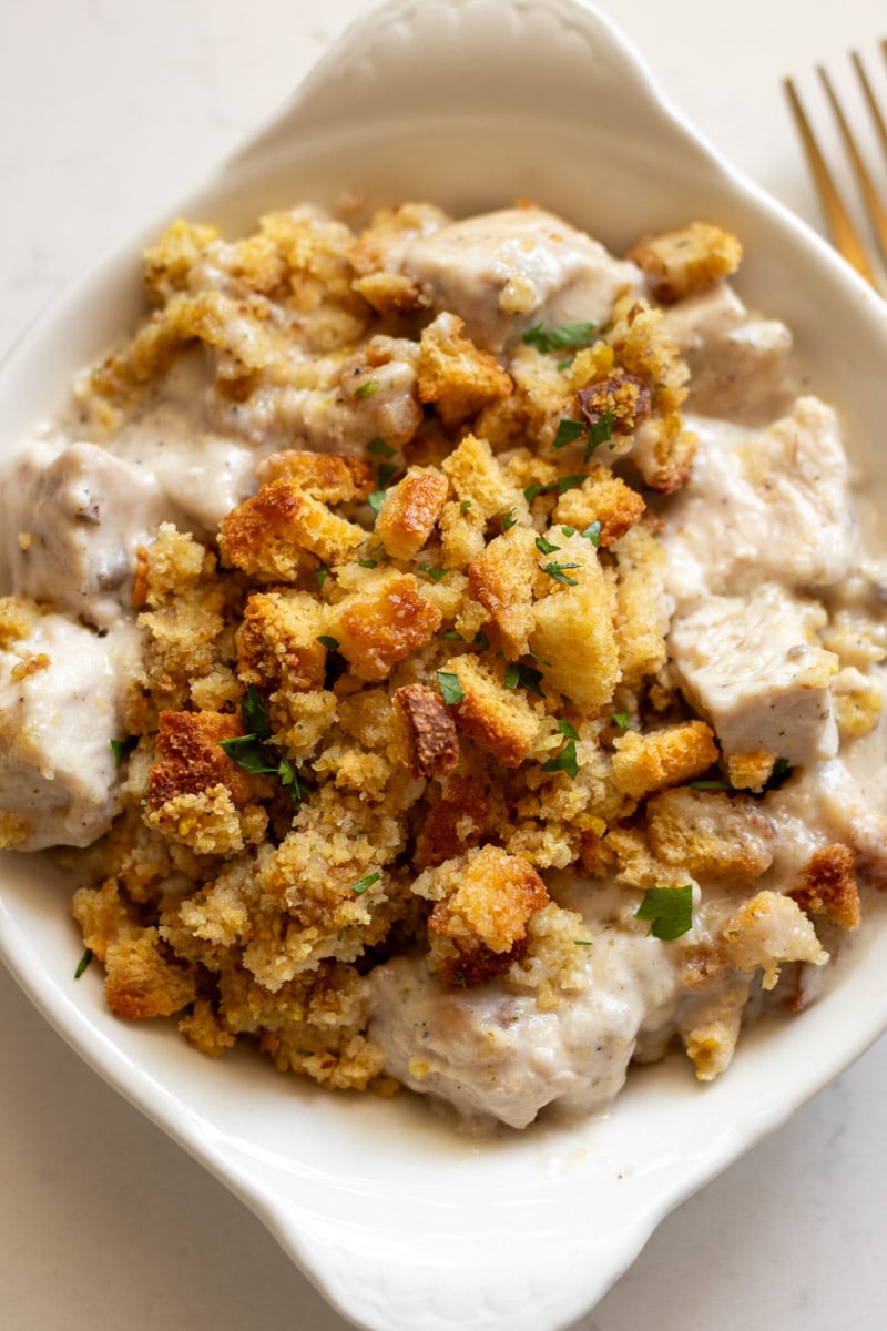 an overhead view of a cream dish filled with golden brown sutffing, tender chicken and a creamy white sauce.