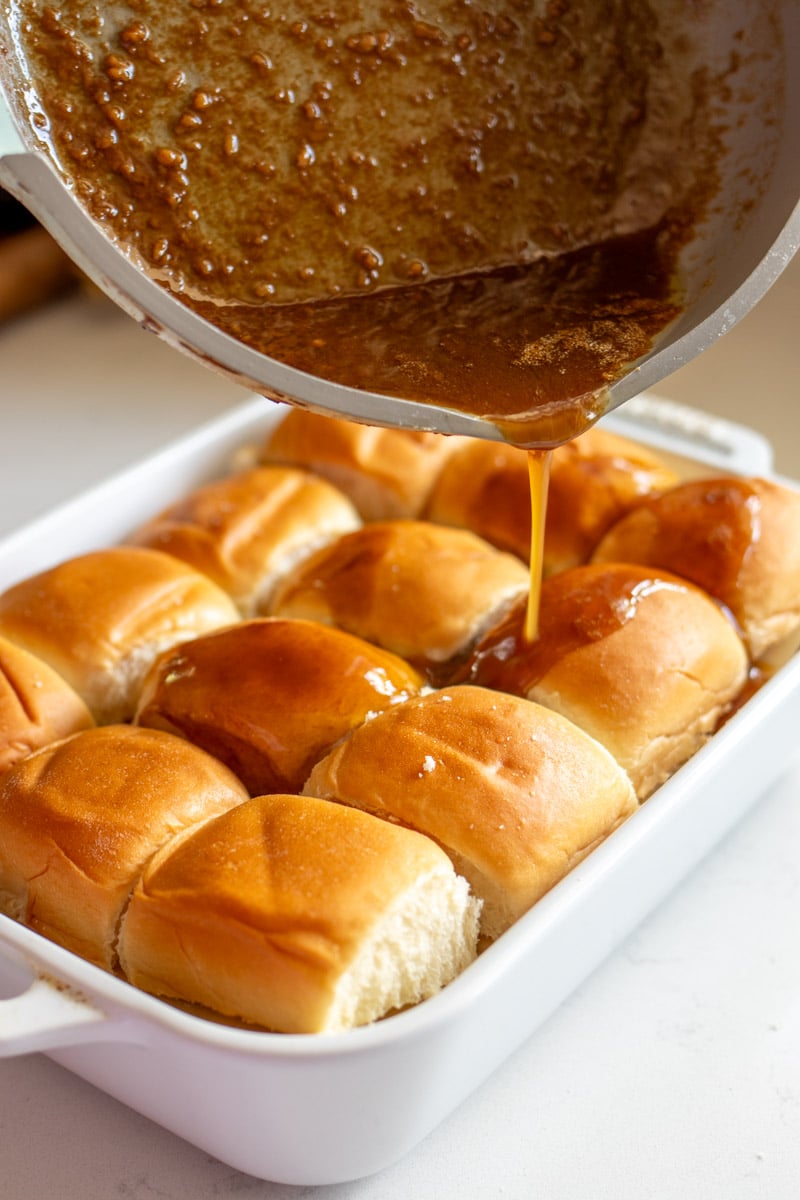 funeral sandwiches brown sugar, dijon, and worchestershire butter sauce being poured on top of slider rolls.