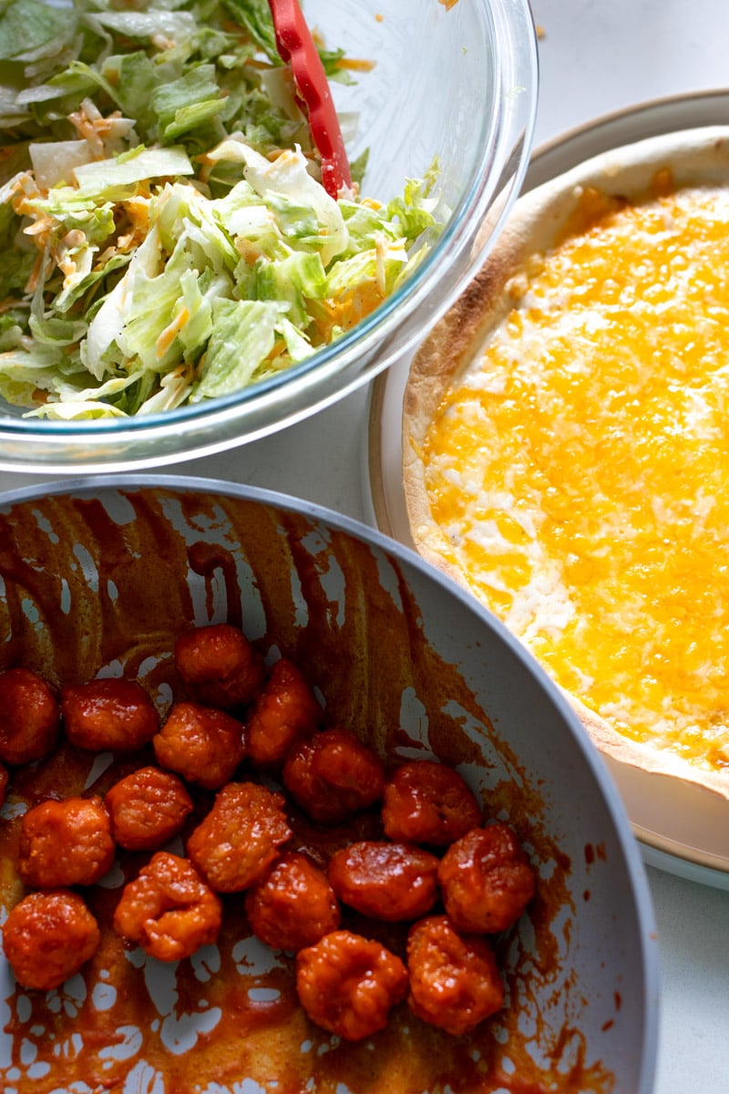 all the ingredients needed to make this buffalo chicken pizza wrap on a white countertop. 
