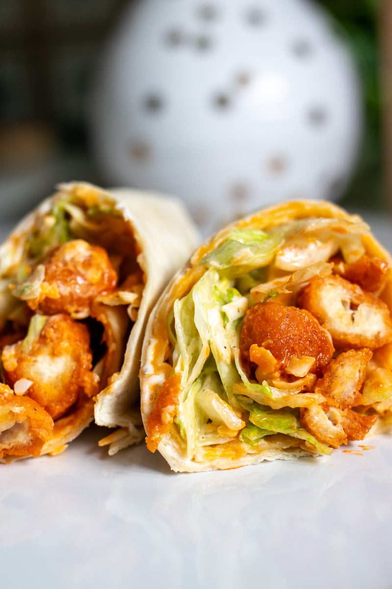 two halves of a buffalo chicken pizza wrap on a white plate. 