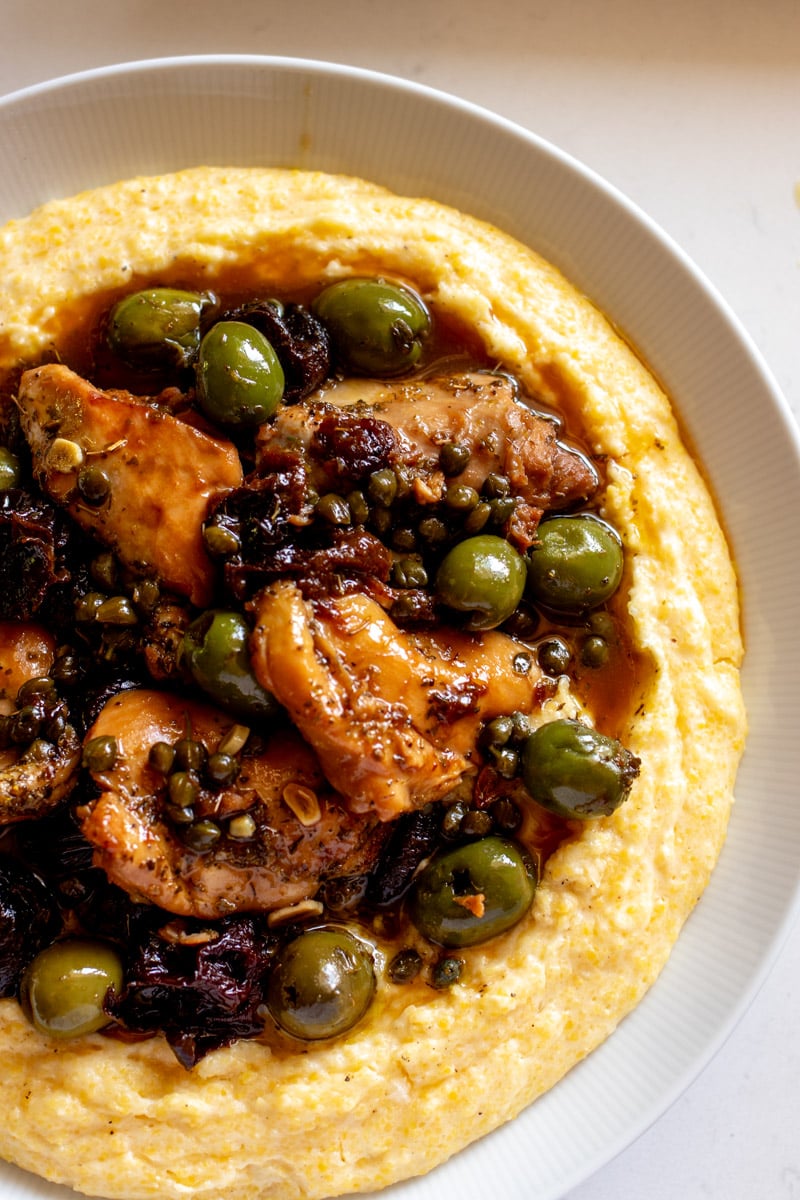 an overhead view of a big bowl of chicken marbella with bright green olives and fudgy prunes.