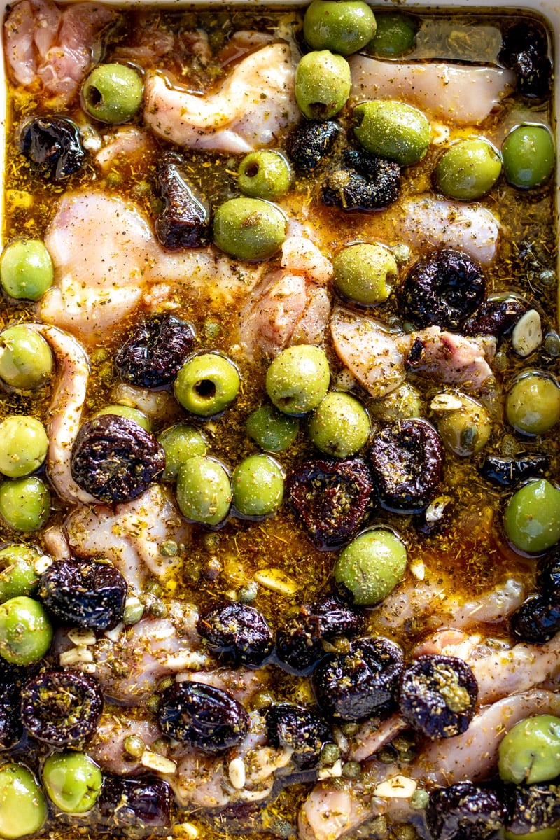 all the ingredients for chicken marbella in a baking dish.