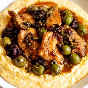 chicken marbella over a bowl of cheesy polenta.