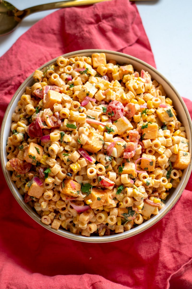 a pink napkin with a bowl of mexican street corn pasta salad on top.