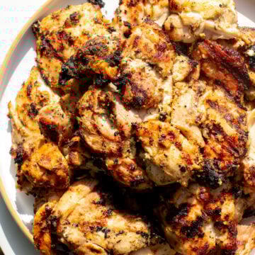 a white plate full of grilled yogurt marinated chicken on a white plate..