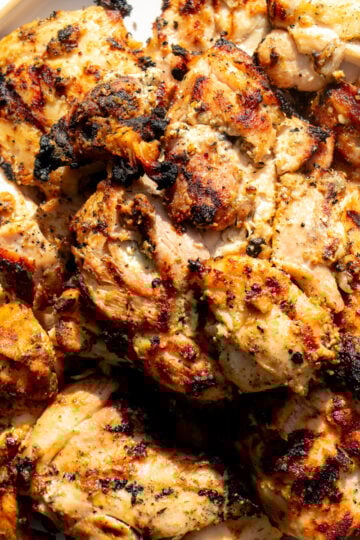 a white plate full of grilled yogurt marinated chicken on a white plate..