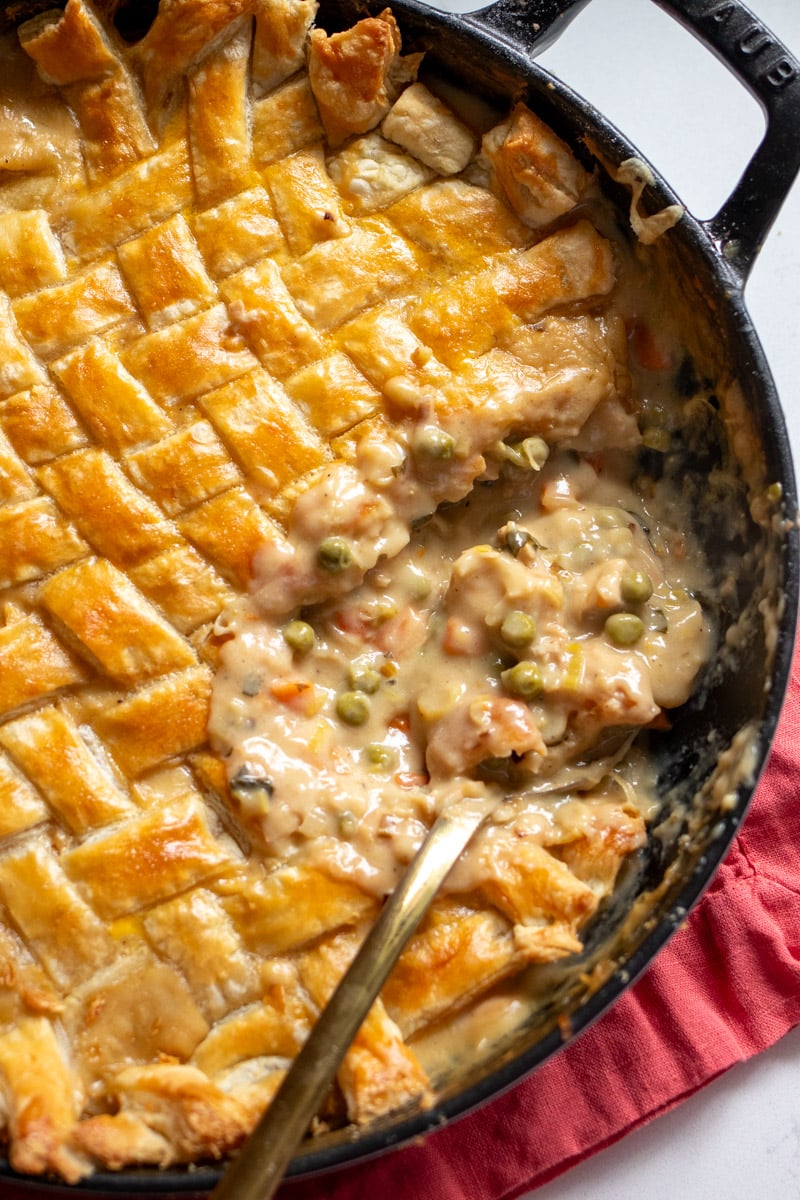 a chicken pot pie with woven crescent dough as the topping with a spoon taking a serving out.