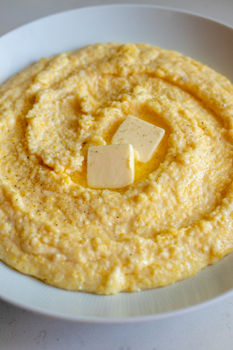 an overhead view of a big bowl of cheesy polenta topped with salt and pepper.