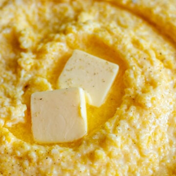 cheesy polenta in a bowl with melted butter on top.