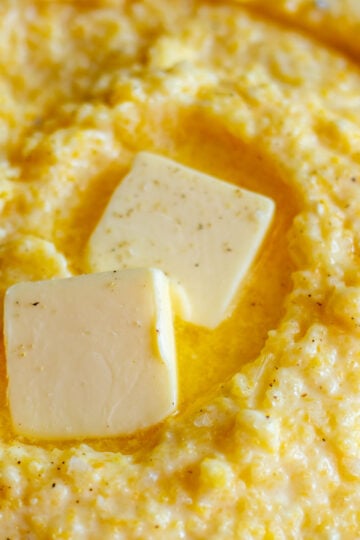 cheesy polenta in a bowl with melted butter on top.
