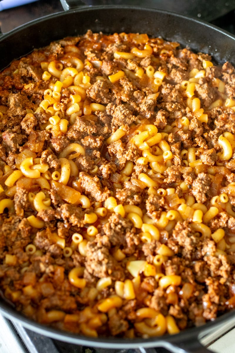 an overhead of a braiser holding an entire recipe of cheesy hamburger mac and cheese.
