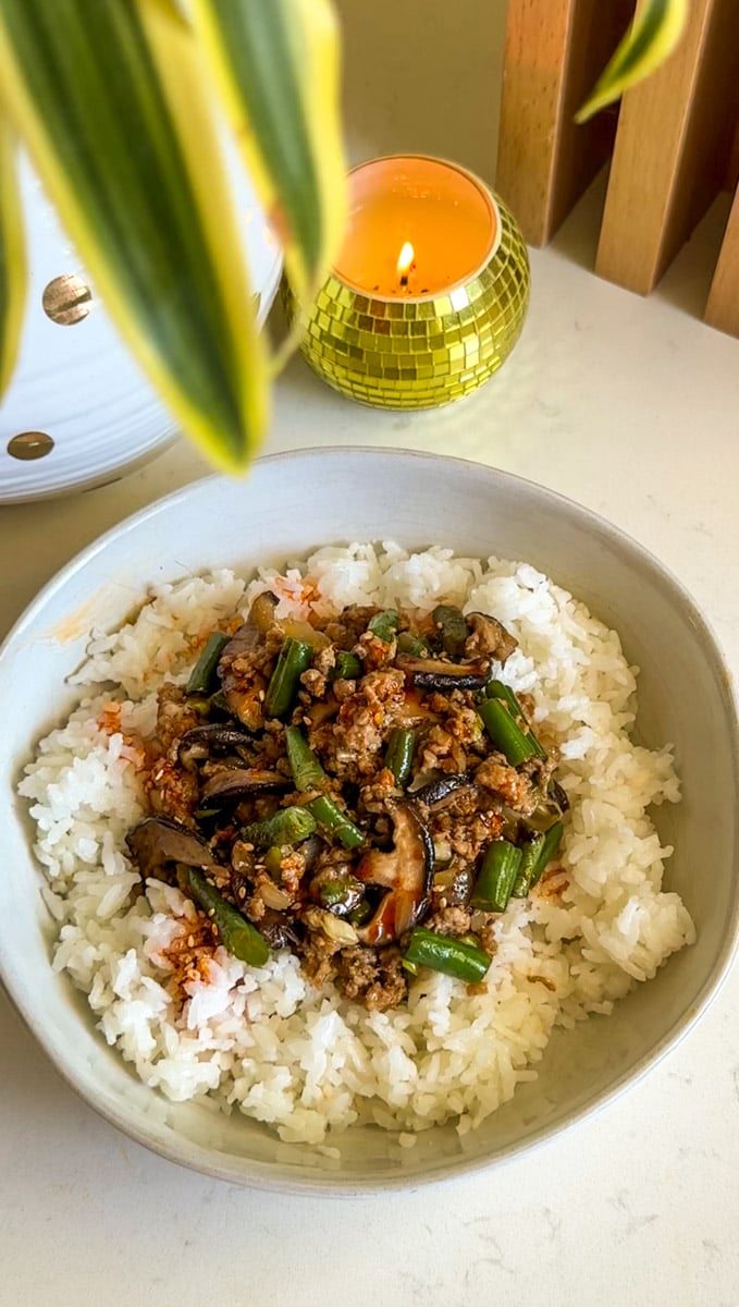 ground pork stir fry recipe with white rice in a bowl on a white countertop.