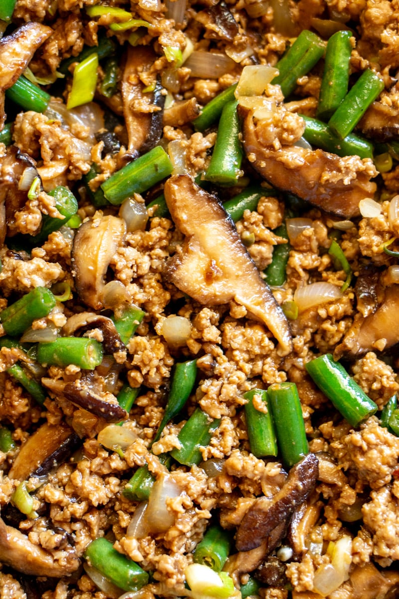 an up close look at the texture of this ground pork stir fry with green beans, mushrooms and onions and asian sauce.