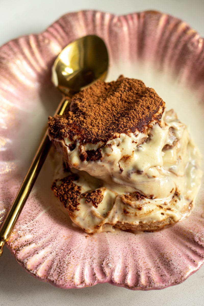 a scoop of pistachio tiramisu on a pink shell plate with a golden spoon.