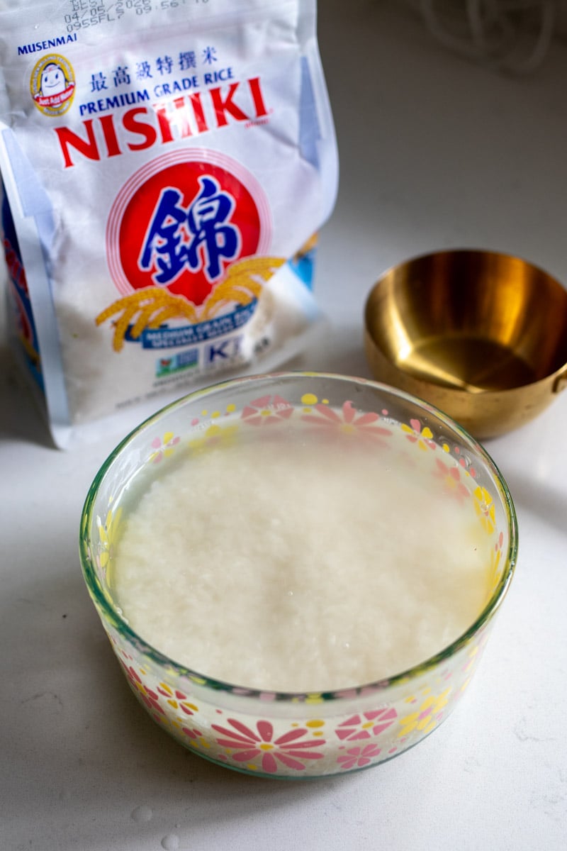 ingredients needed to make sushi rice on a white countertop.