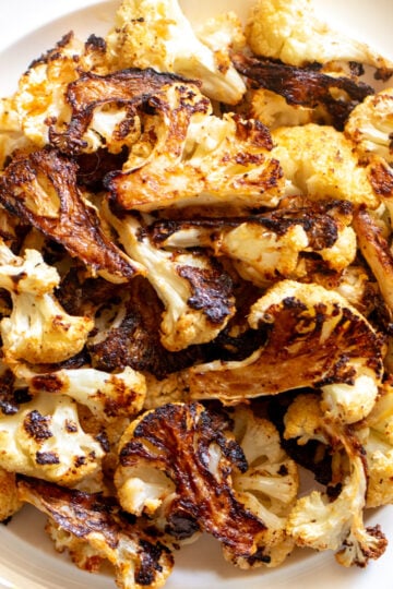 crispy roasted cauliflower on a white plate with a blue rim.