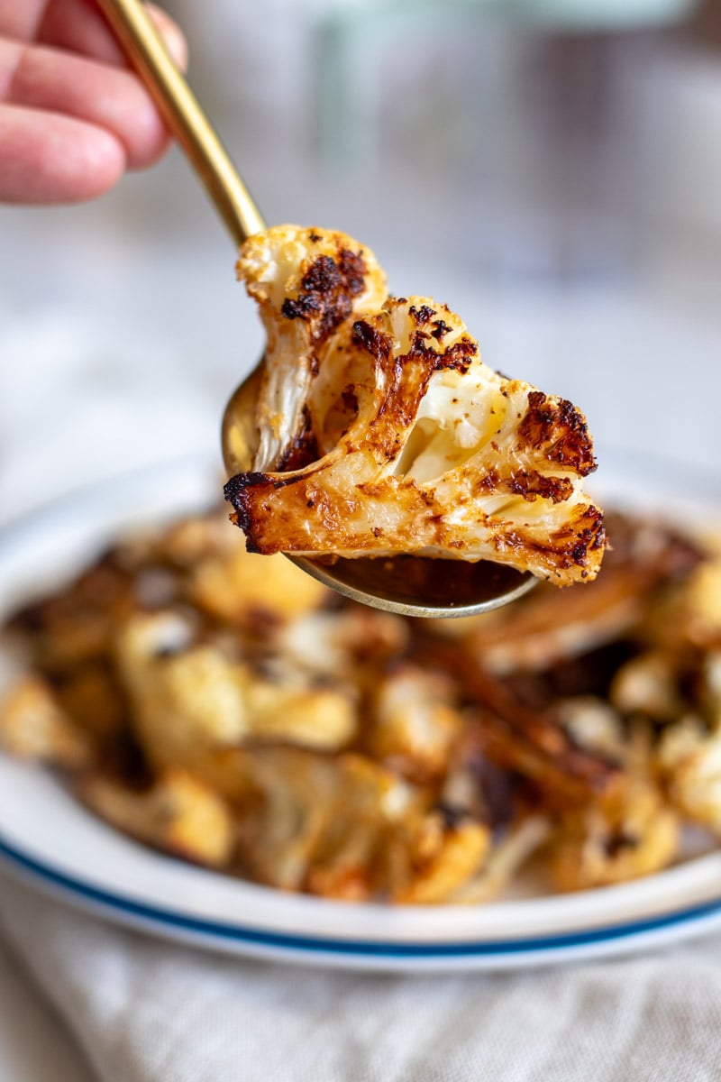 a spoon holding a singular piece of crispy cauliflower - showing off it's crispy edge.