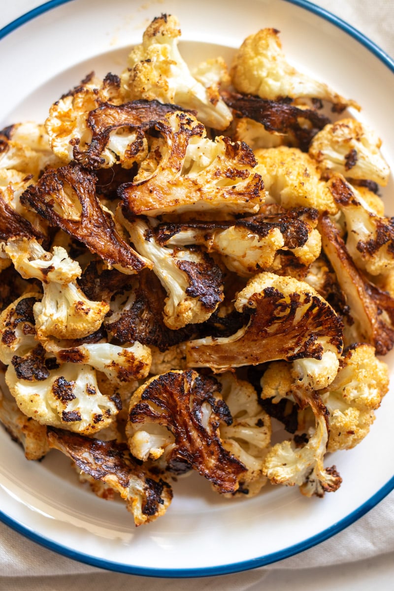 an overhead view of a white plate filled with crispy roasted cauliflower.