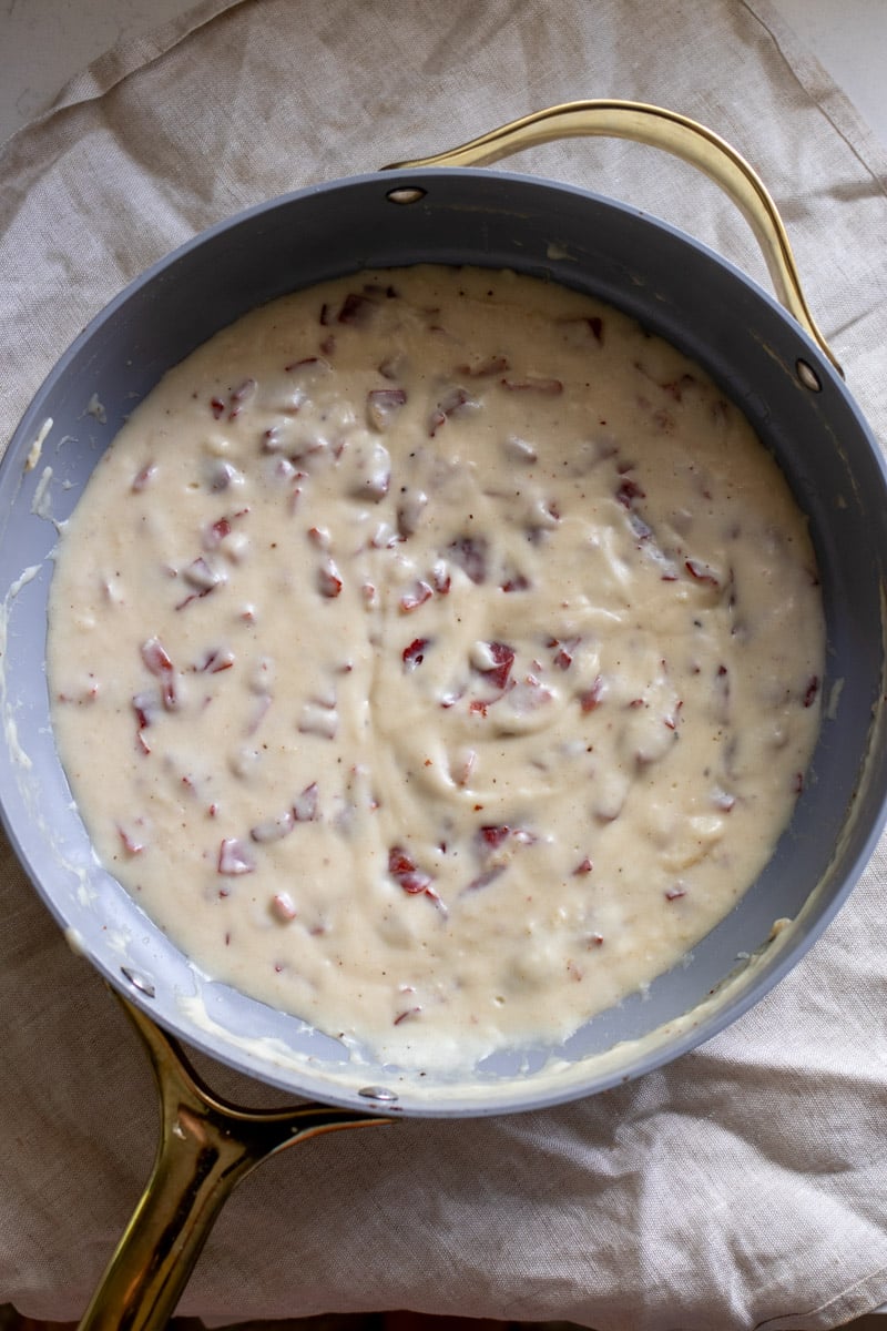 a grey skillet full of creamy chipped beef sauce over a tan towel.