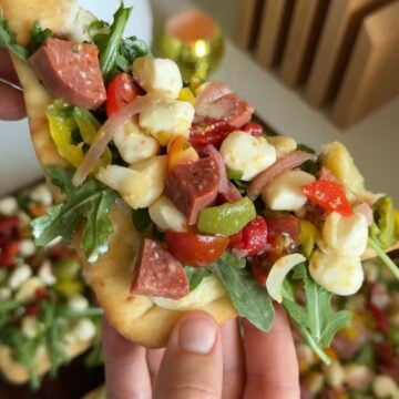 a piece of flatbread with salad and jar-cuterie on top.