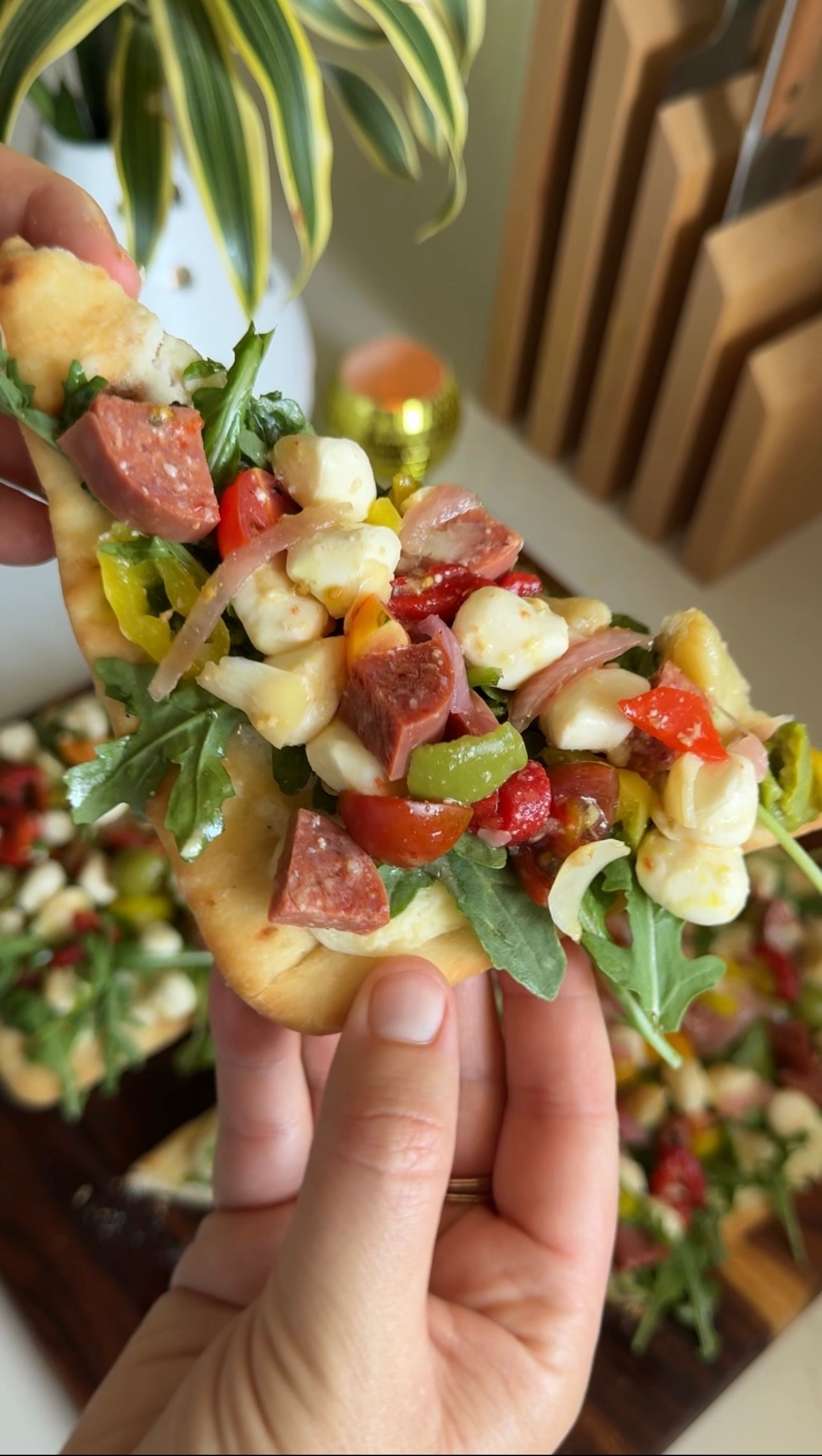 a piece of flatbread with salad and jar-cuterie on top.