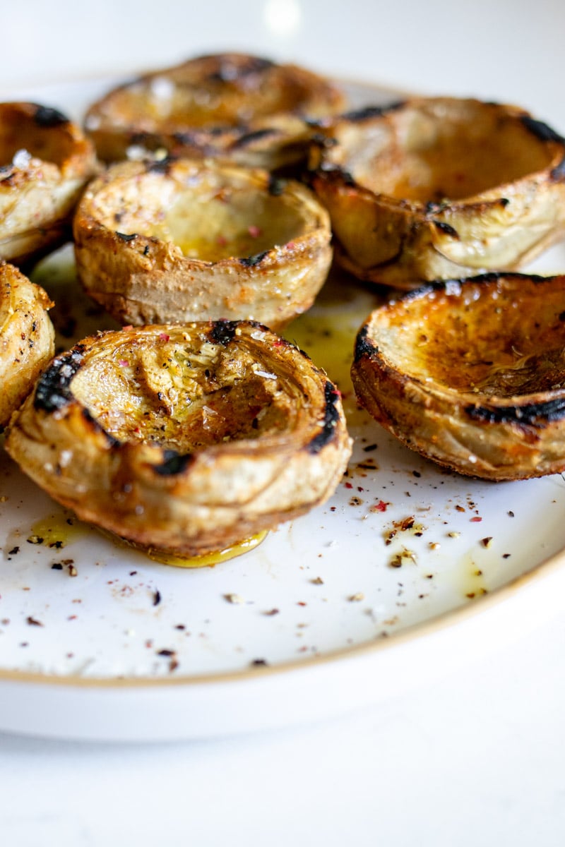 a platter of grilled artichokes with seasoning, lemon and olive oil.