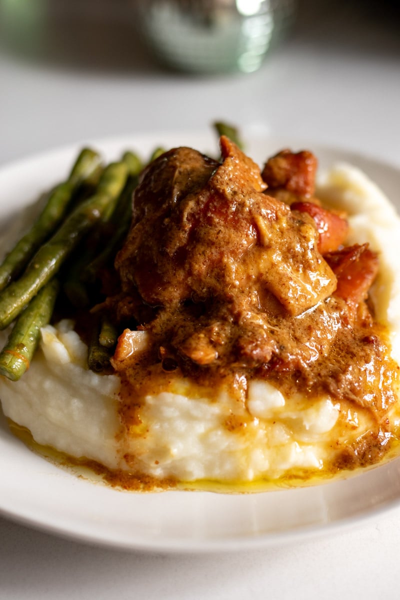 a plate of honey mustard slathered chicken thighs that are fall apart tender with mashed potatoes and green beans.
