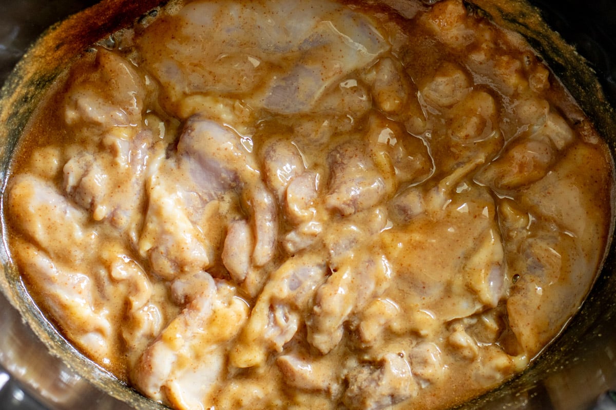 a crockpot filled with chicken thighs and honey mustard sauce.