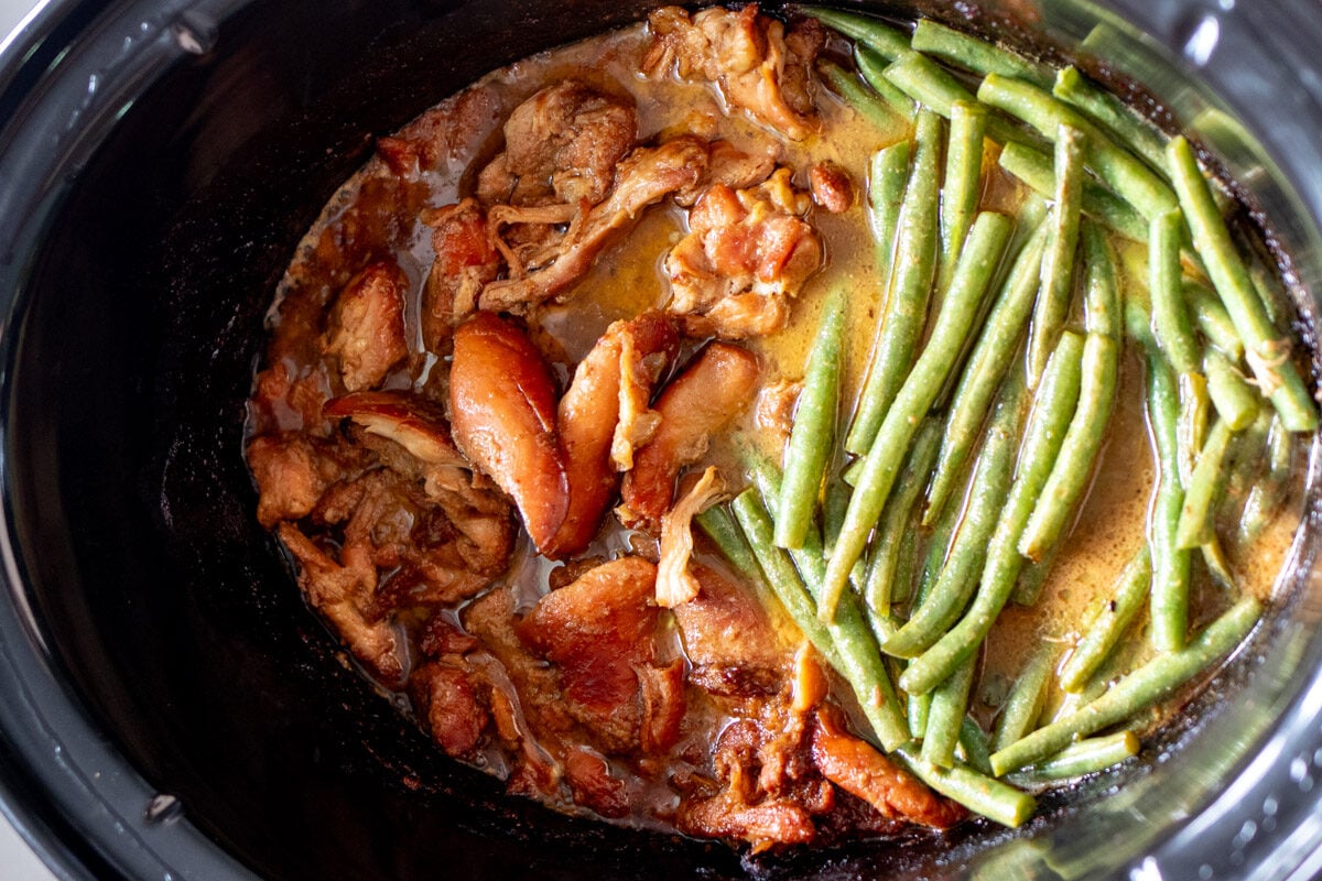 caramelized and fall apart tender honey mustard chicken thighs in a black crockpot.