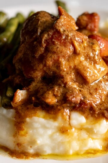 a plate of honey mustard slathered chicken thighs that are fall apart tender with mashed potatoes and green beans.