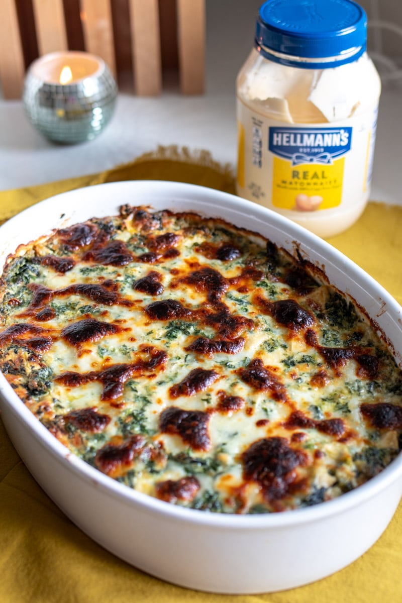 a big white baking dish full of cheesy hot spinch artichoke dip. 