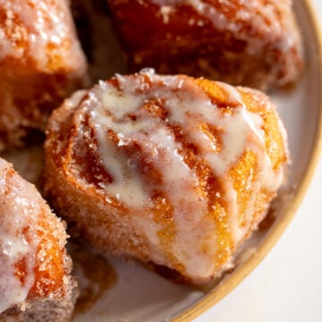 Disney's deep fried hawaiian rolls on a plate topped with cinnamon sugar and sweetened condensed milk.