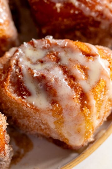 Disney's deep fried hawaiian rolls on a plate topped with cinnamon sugar and sweetened condensed milk.