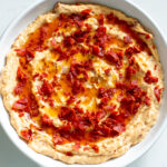 a white bowl full of creamy pepperoni caesar dip.