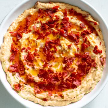 a white bowl full of creamy pepperoni caesar dip.