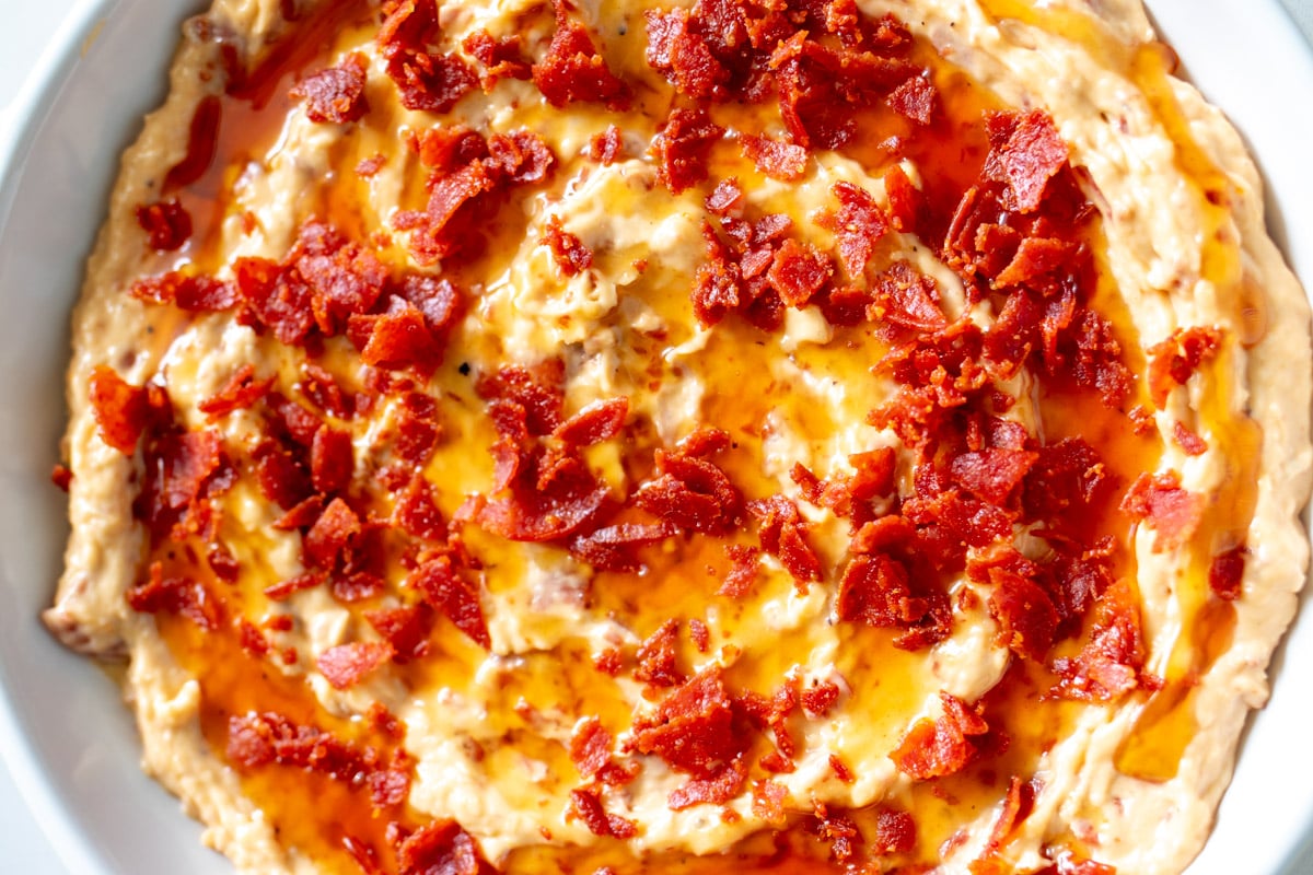 an up close look at this sweet heat pepperoni caesar dip in a white bowl.