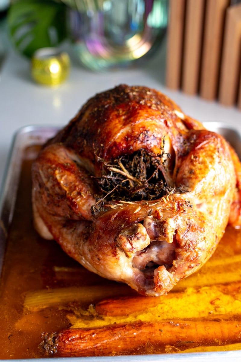 the read end of a stuffed roasted turkey with herbs sticking out of it.