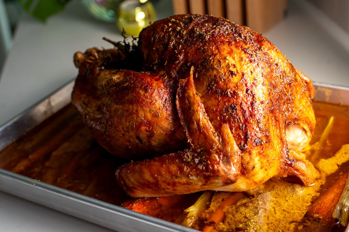 a golden brown butter and herb roasted turkey sitting in the sunlight. 