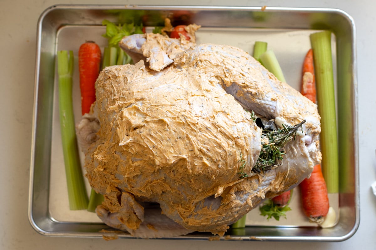 a compound butter with herbs rubbed all over a whole turkey.