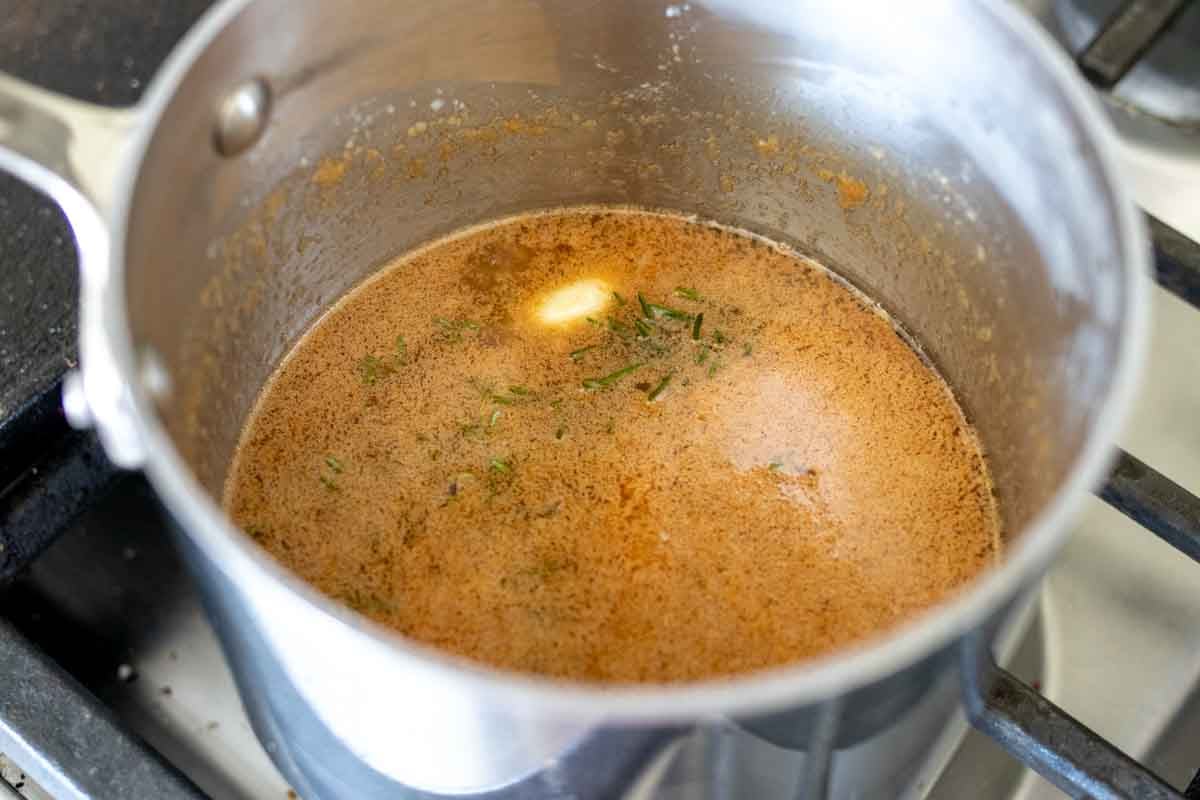 butter, herbs, garlic and chicken boullion in a pot simmering - al the ingredients to make turkey injector marinade.